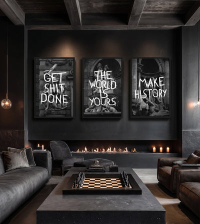 History in the Making Collection room mockup: three monochrome classical architecture artworks with GET SHIT DONE, THE WORLD IS YOURS and MAKE HISTORY lettering, shown above a linear fireplace and chess table.