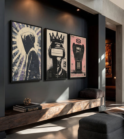 Gods We Made Collection room mockup: three stencil-style artworks showing a hooded figure, a crowned headset wearer and a winged tower, shown above a wooden bench.