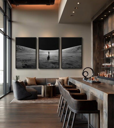Into the Silence Collection room mockup: three monochrome lunar landscapes with a solitary astronaut in the center panel, shown beside a bar and lounge area.