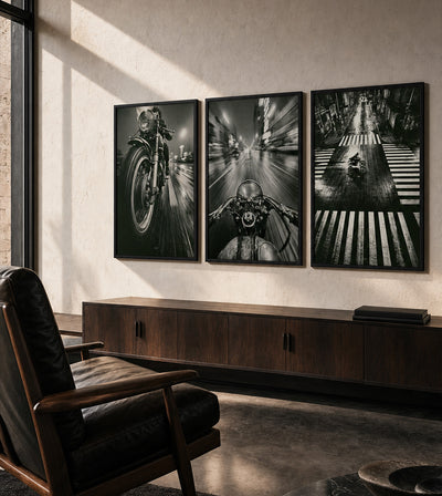 Built to Vanish Collection room mockup: three monochrome motorcycle artworks showing a front wheel, rider-view cockpit and overhead street crossing, shown above a long wooden cabinet.