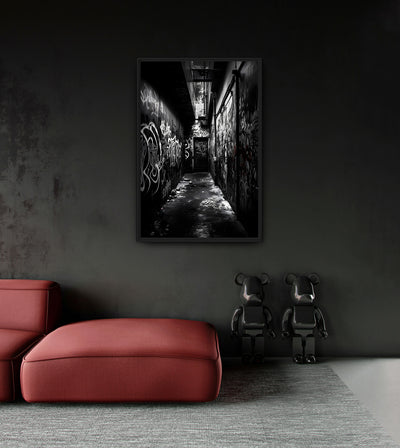Richness in Poverty room mockup: a monochrome narrow alley covered in graffiti, shown above a red chaise.