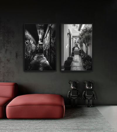 One And The Same Bundle room mockup: two monochrome passage artworks contrasting a graffiti alley and a bright plant-lined courtyard, shown above a red chaise.